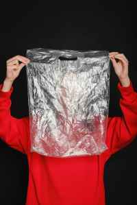 person wearing red top holding clear plastic bag